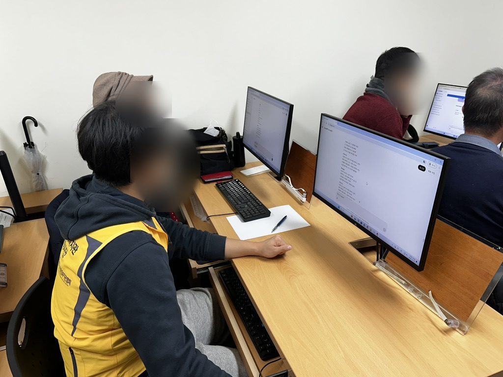 학생이 어르신 옆에서 1:1로 컴퓨터 사용을 돕는 모습